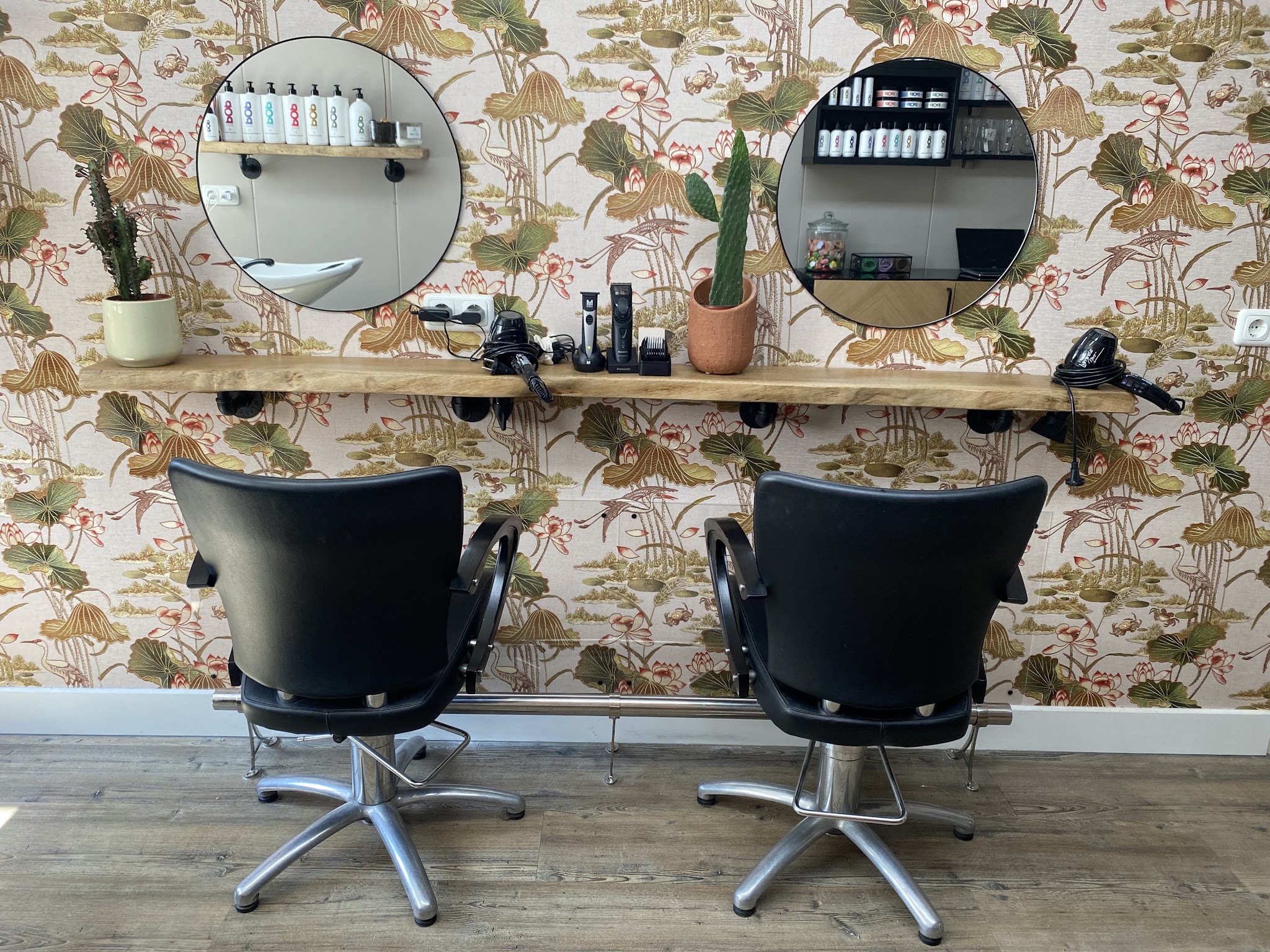De werkplek van Haarstudio 16 met het botanische behang en de houten wandplank
